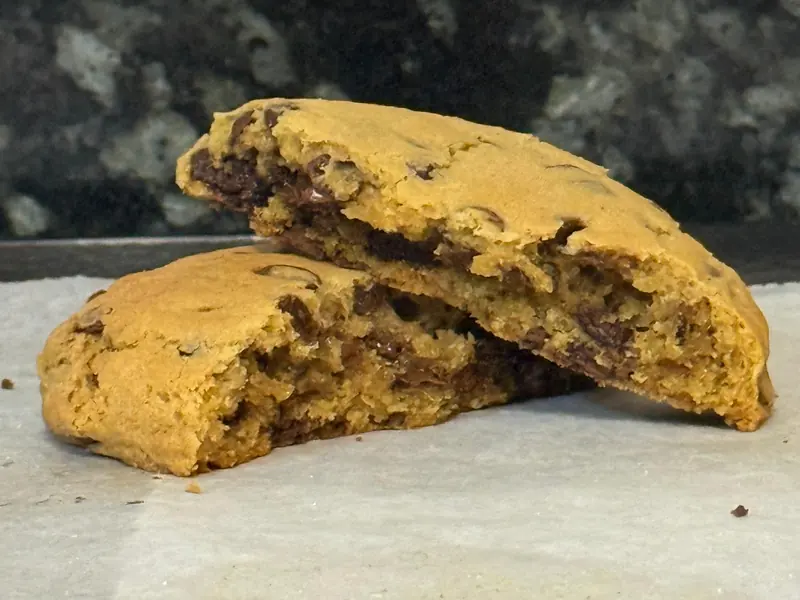 A Classic Choc Chip cookie broken in half to show its soft centre